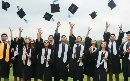 High school graduates celebrating with caps in the air, symbolizing new education grants and future opportunities.